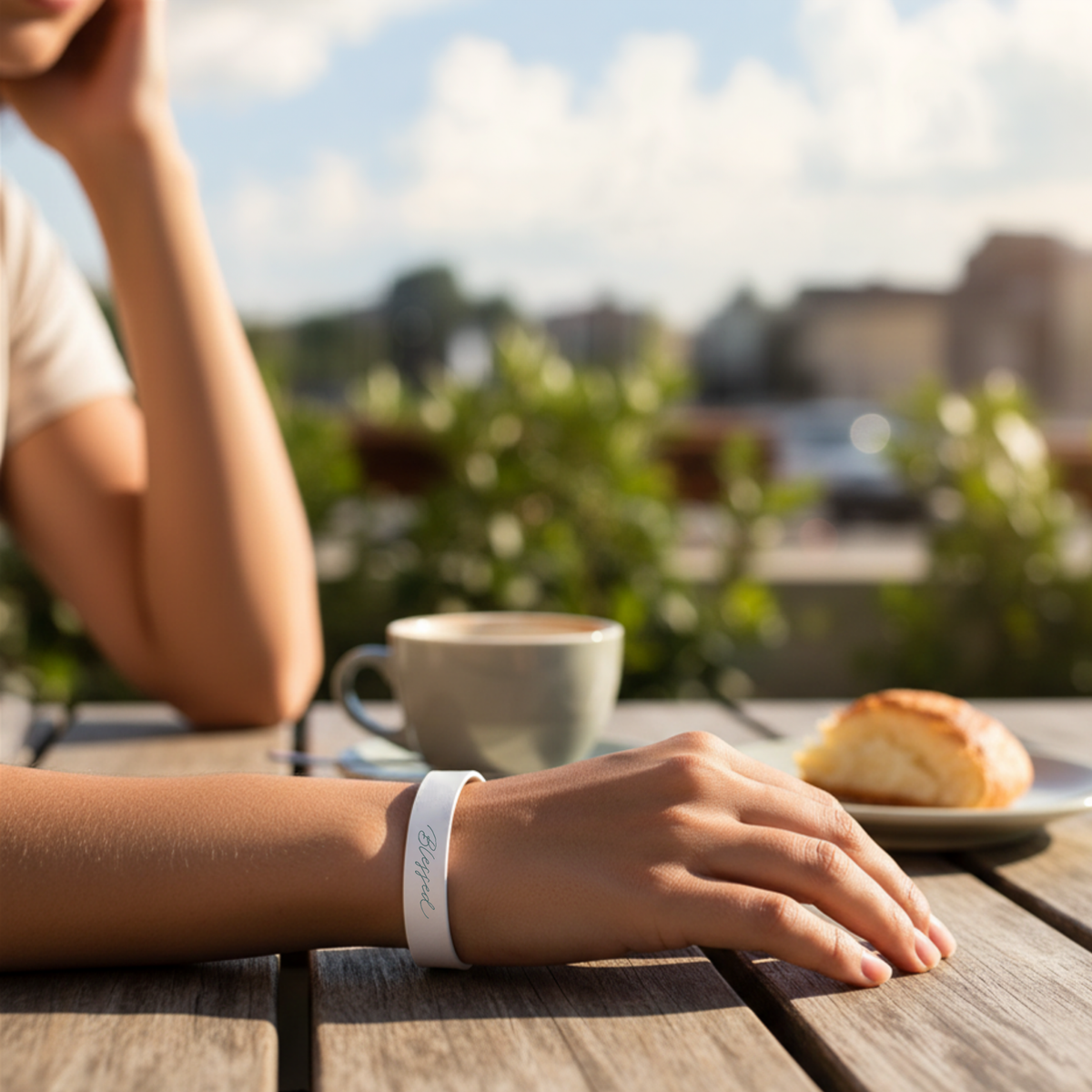 Person sitting at a table with a cup of coffee and pastry, blurred outdoor background by CTA Christ to All & CTA Gifts.