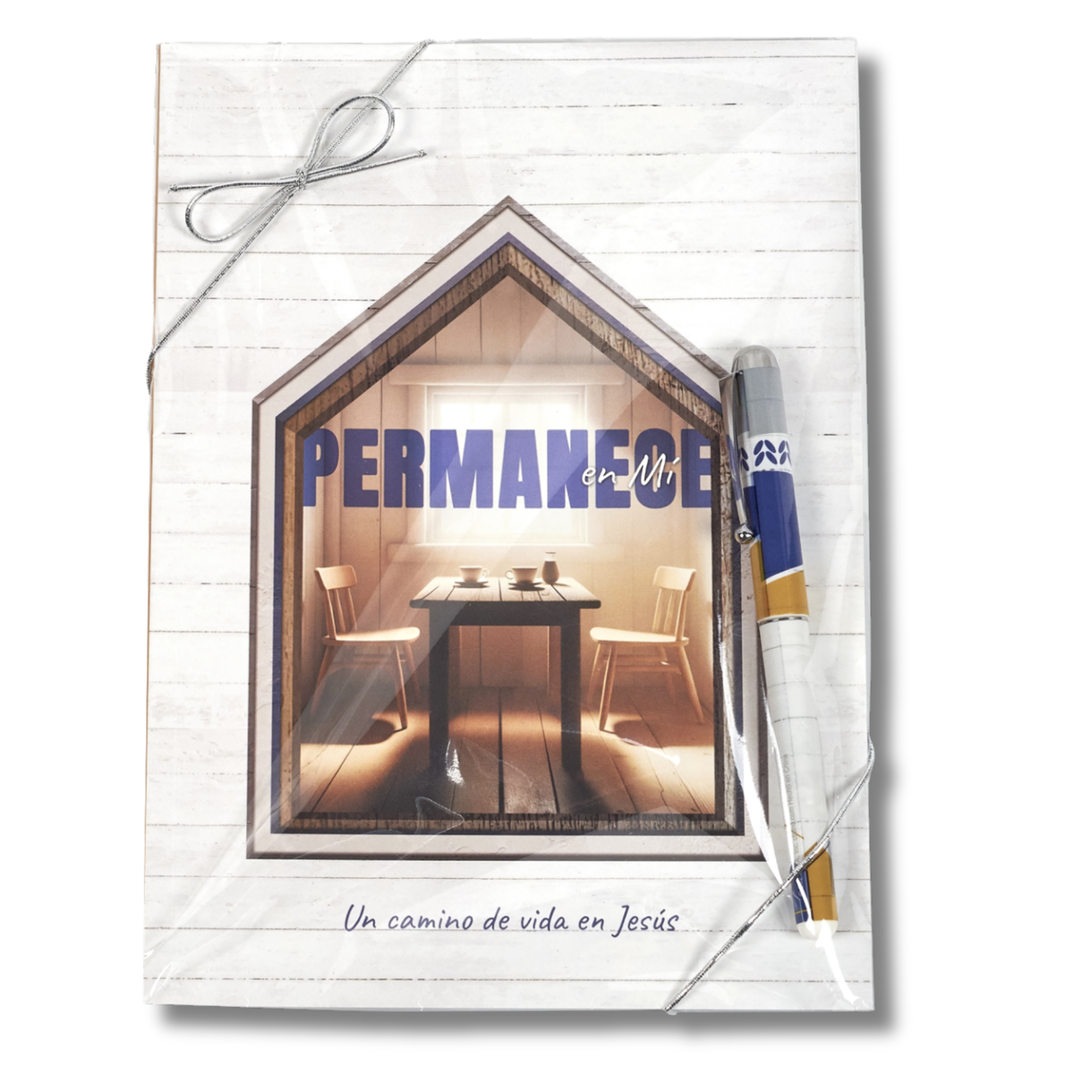 A Spanish-language Bible study workbook titled 'PERMANECE en MÍG' featuring a house-shaped window graphic showing a dining room interior. The workbook has a white wood-textured cover, a silver string bow at the top, and a blue, white, and gold pen tucked on the right side by CTA Christ to All & CTA Gifts.