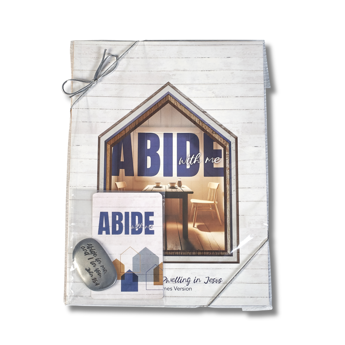 A packaged Bible book set titled 'ABIDE with me' by John MacArthur, featuring a white wood-textured cover with a house-shaped window graphic, a small white card, and a silver metal bookmark tied with gray string on a white background by CTA Christ to All & CTA Gifts.