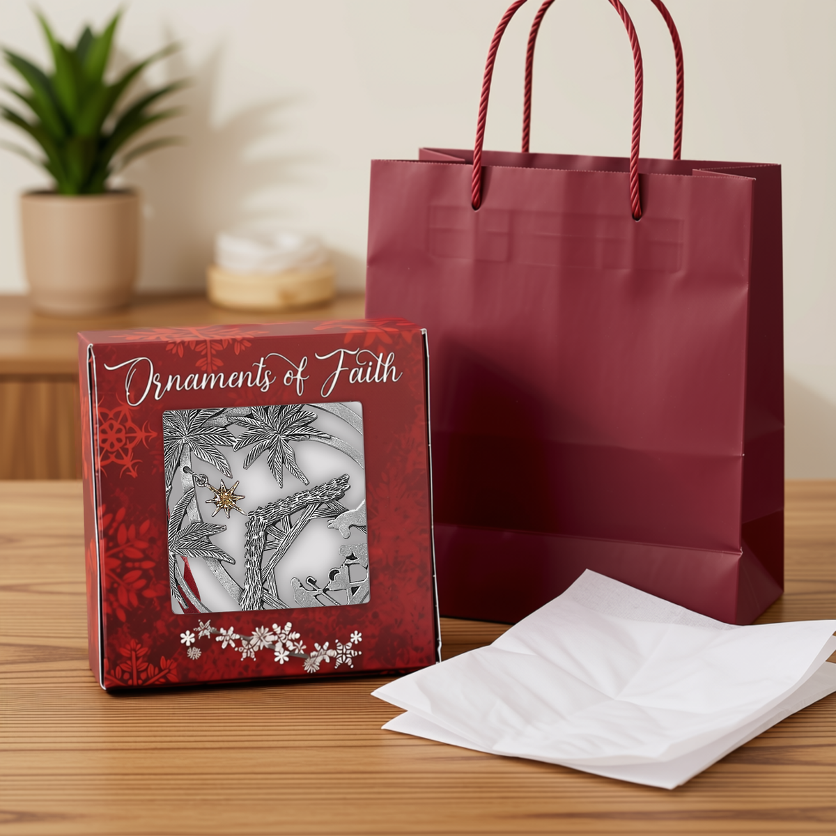 Red "Ornaments of Faith" gift box displaying a pewter-finish Nativity ornament, shown alongside a red gift bag and white tissue paper for easy gift giving by CTA Christ to All and CTA Gifts. Ornaments of Faith® is trademarked.