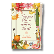 A devotional prayer journal titled 'Amazing Grace for Woman's Heart' with a green pen tucked into the cover, decorated with illustrations of citrus fruits, pink flowers, and butterflies on a white background by CTA Christ to All & CTA Gifts.