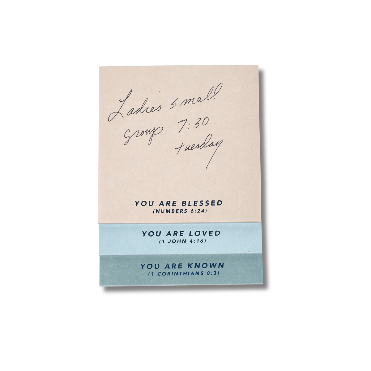 A square greeting card or note with a warm beige top section featuring handwritten black ink text and printed black text reading 'YOU ARE BLESSED (NUMBERS 6:24)', and a light blue bottom section with printed text reading 'YOU ARE LOVED (1 JOHN 4:18)' and 'YOU ARE KNOWN (1 CORINTHIANS 8:2)' by CTA Christ to All & CTA Gifts.