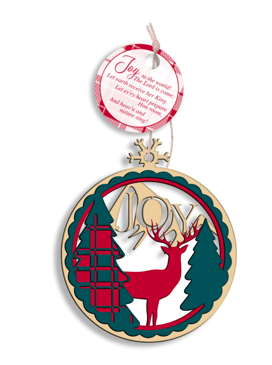 A laser-cut wooden ornament with a red deer, green trees, and the text 'JOY' displayed, designed with a rustic string hanger.