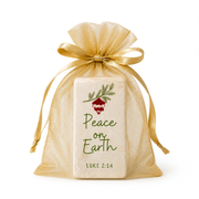 A rectangular cream-colored soap bar wrapped in a clear gold organza pouch tied with a gold ribbon, featuring a red berry illustration and the text 'Peace on Earth LUKE 2:14' on the front by CTA Christ to All and CTA Gifts.