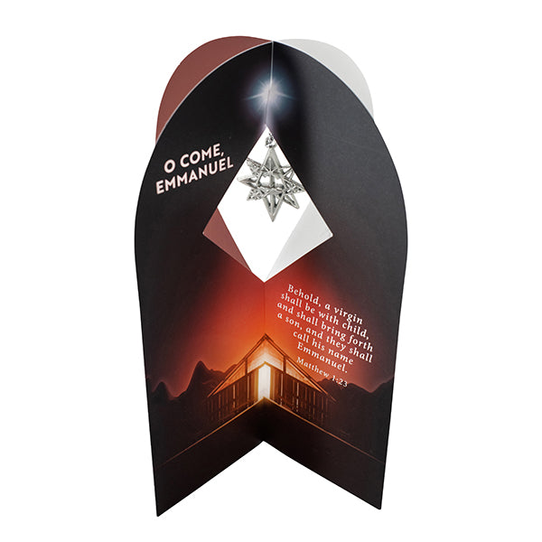 Christian Christmas ornament gift card shown partially open, featuring a silver-tone star ornament suspended within a diamond-shaped display window. The card displays a nativity-inspired stable illuminated beneath a bright star, along with the text “O Come, Emmanuel” and Matthew 1:23: “Behold, a virgin shall be with child, and shall bring forth a son, and they shall call his name Emmanuel" by CTA Christ to All and CTA Gifts.