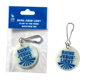 Glow-in-the-dark backpack tag with 'Shine Jesus' Light' text, displayed with packaging.
