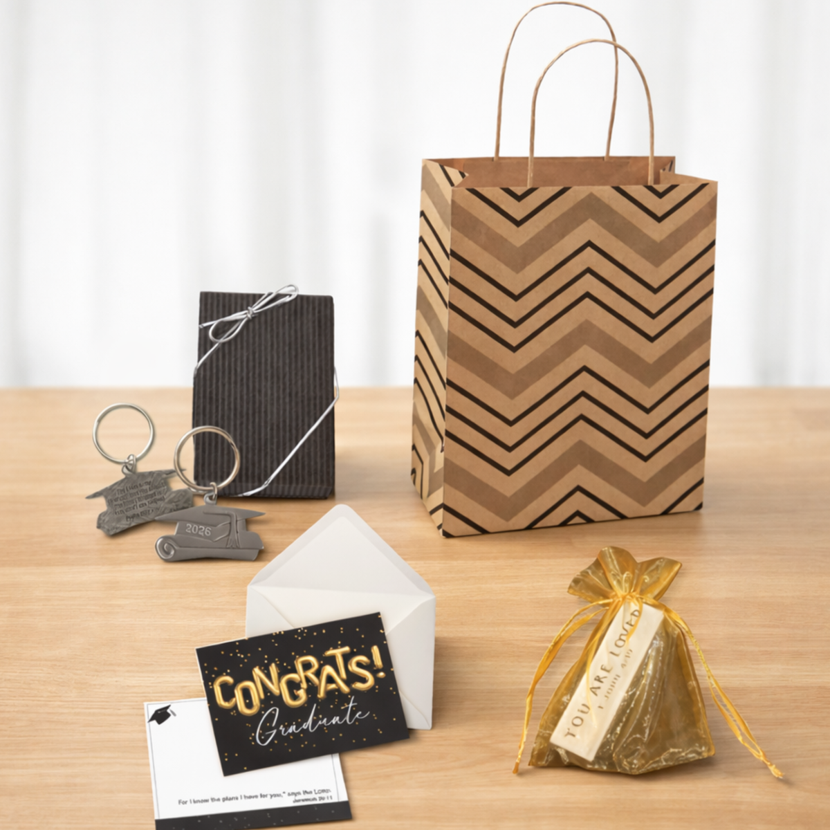 Graduation-themed gift items including a keychain, card, and gift bag on a wooden surface.