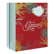 A red gift bag with a festive holiday design, featuring the word 'Grace' in white script, snowflakes, pine branches, berries, and a circular hanging tag with a mirror by CTA Christ to All & CTA Gifts.