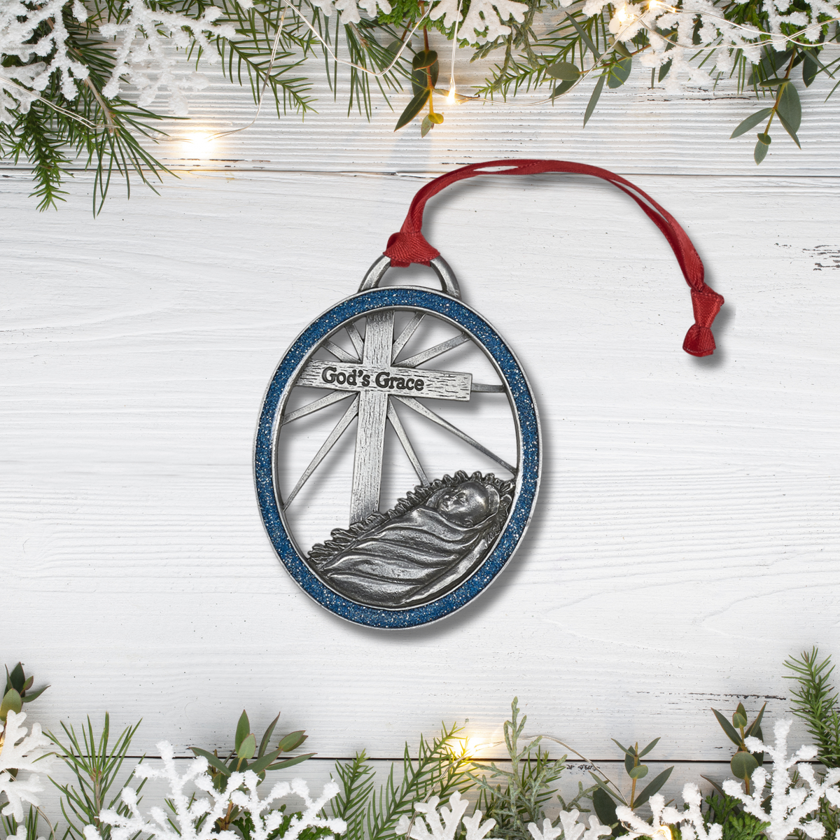 Decorative Christmas ornament with 'God's Grace' text on a white wooden background with greenery.