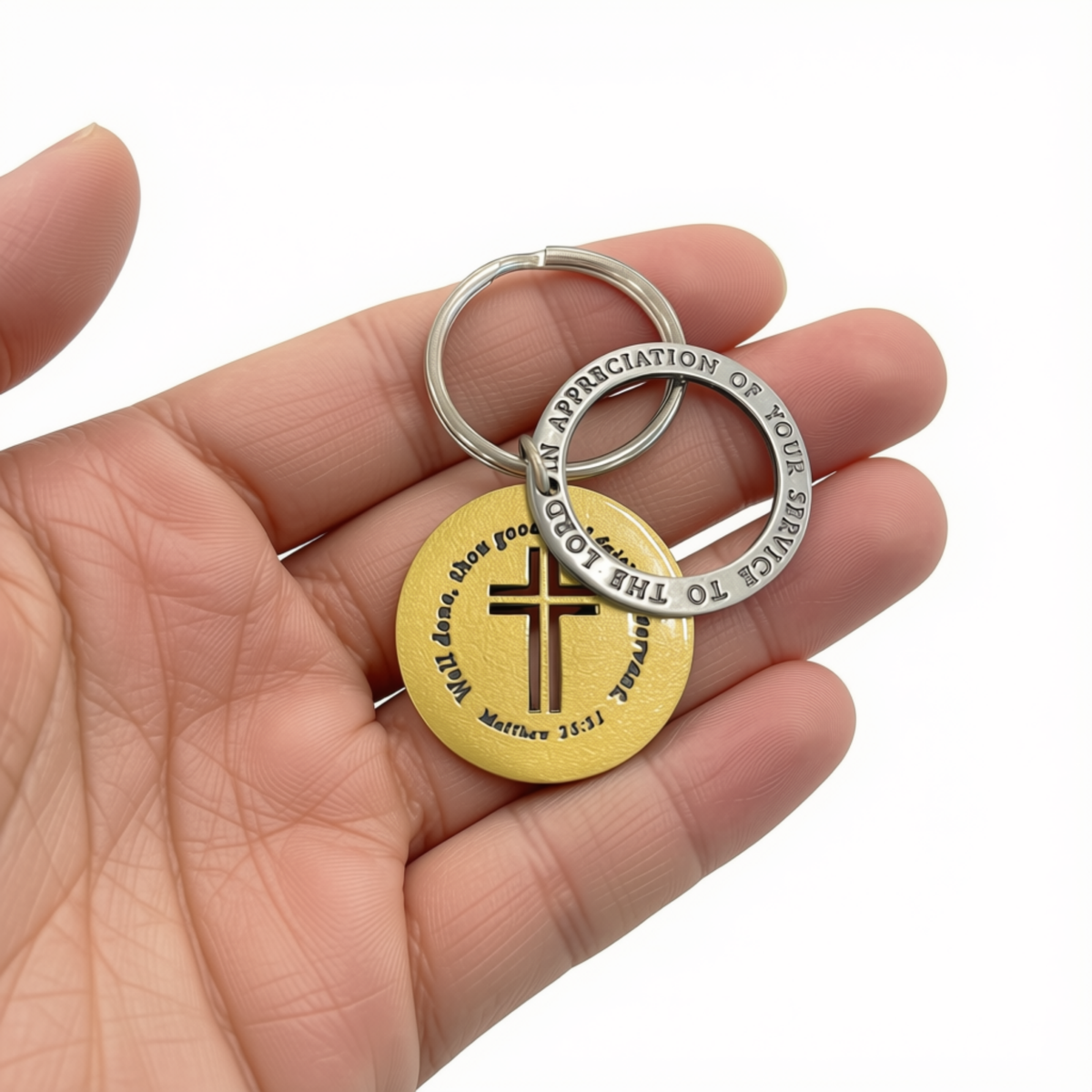 A hand holding two interlocking keychains: one round gold-toned with a cross and Bible verse, and one silver-toned with engraved text reading 'An Appreciation of Your Prayer to the Lord' and 'Matthew 25:31' by CTA Christ to All and CTA Gifts.
