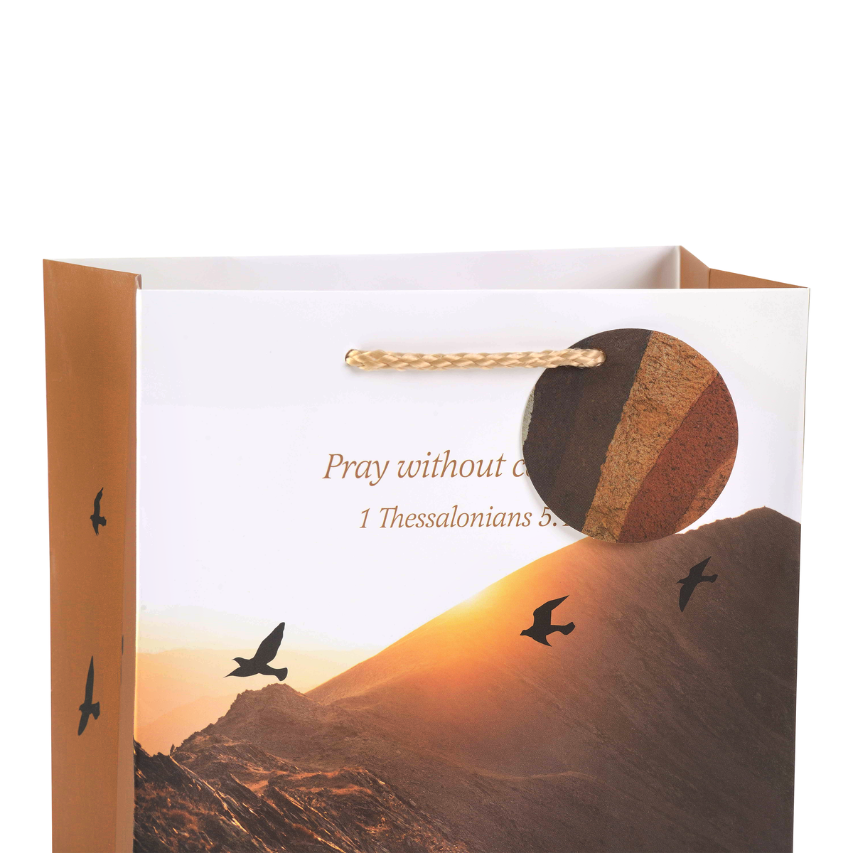 A white and brown paper gift bag featuring a printed mountain sunset scene with birds and the text 'Pray without by CTA Christ to All and CTA Gifts.