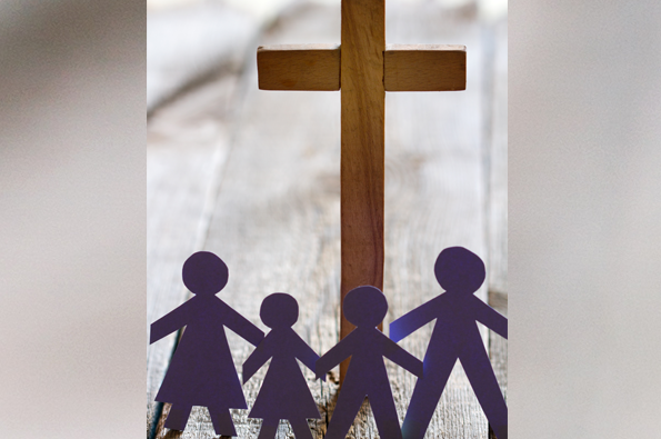 Paper cutouts of parents and two children at the foot of a cross symbolizing family ministry