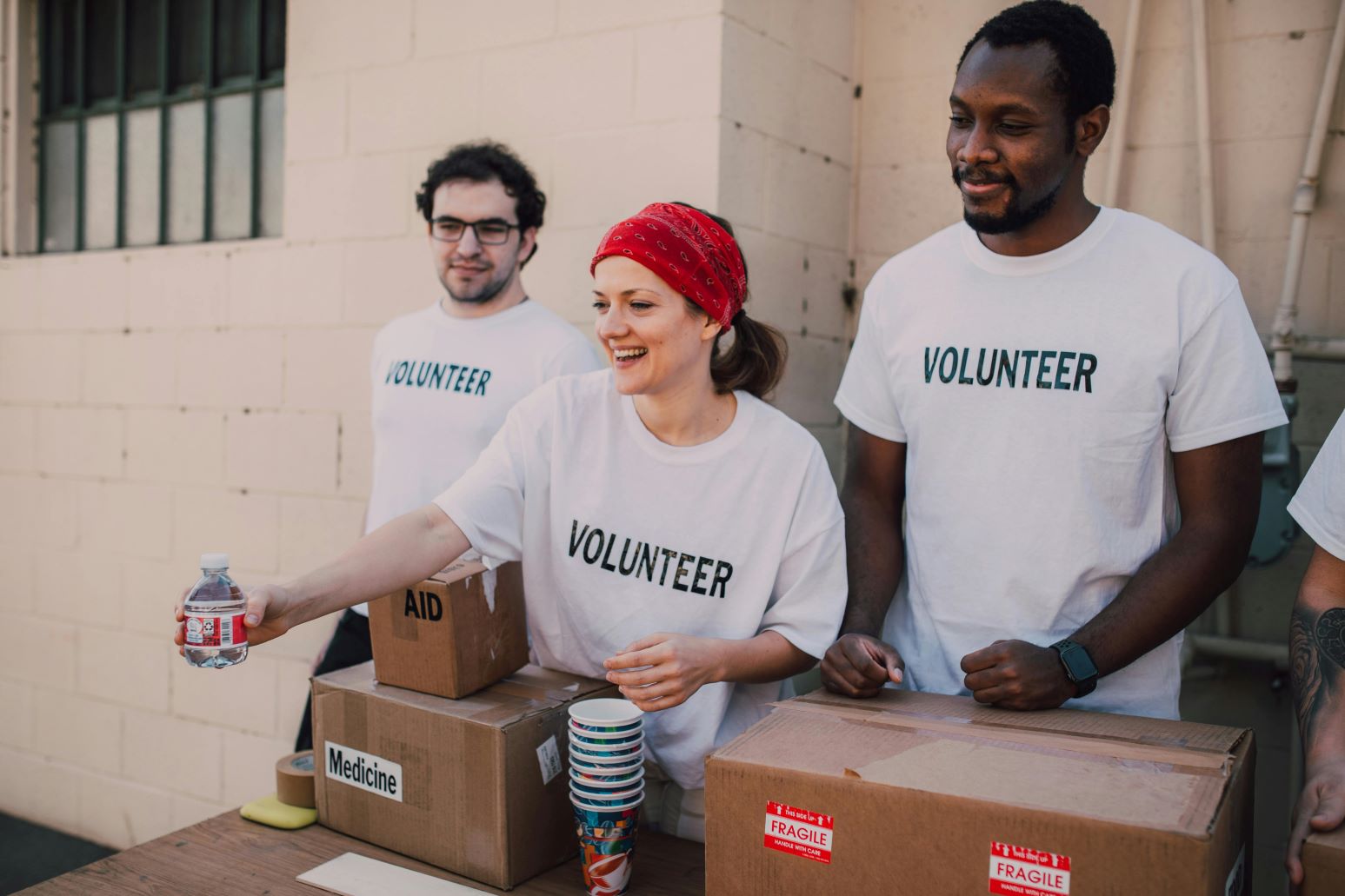 Group of 3 volunteers handing out medicine and water