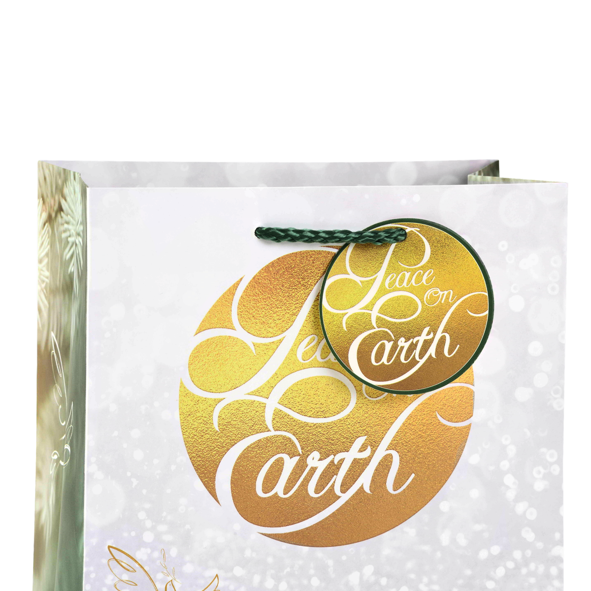 A white gift bag with a large gold foil circle reading 'Peace on Earth' in white script, a matching round hanging tag, and a green rope handle, shown on a white background by CTA Christ to All and CTA Gifts.