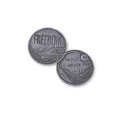 Two round silver-toned metal coins or medallions shown on a plain white background. One coin is engraved with the word "FREEDOM" and a landscape design, and the other reads "The truth will set you free.