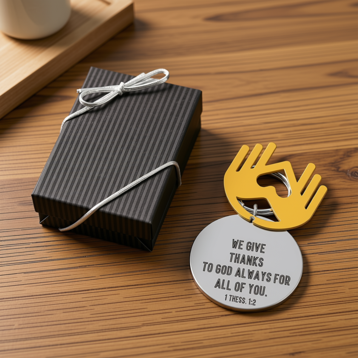 A round silver metal thank-you tag with a yellow hand-shaped loop, printed with the Bible verse 'WE GIVE THANKS TO GOD ALWAYS FOR ALL OF YOU' by CTA Christ to All and CTA Gifts.