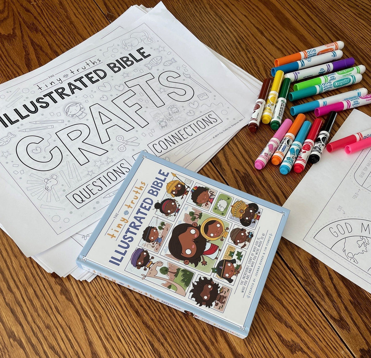 Illustrated Bible with coloring pages and markers on a wooden surface