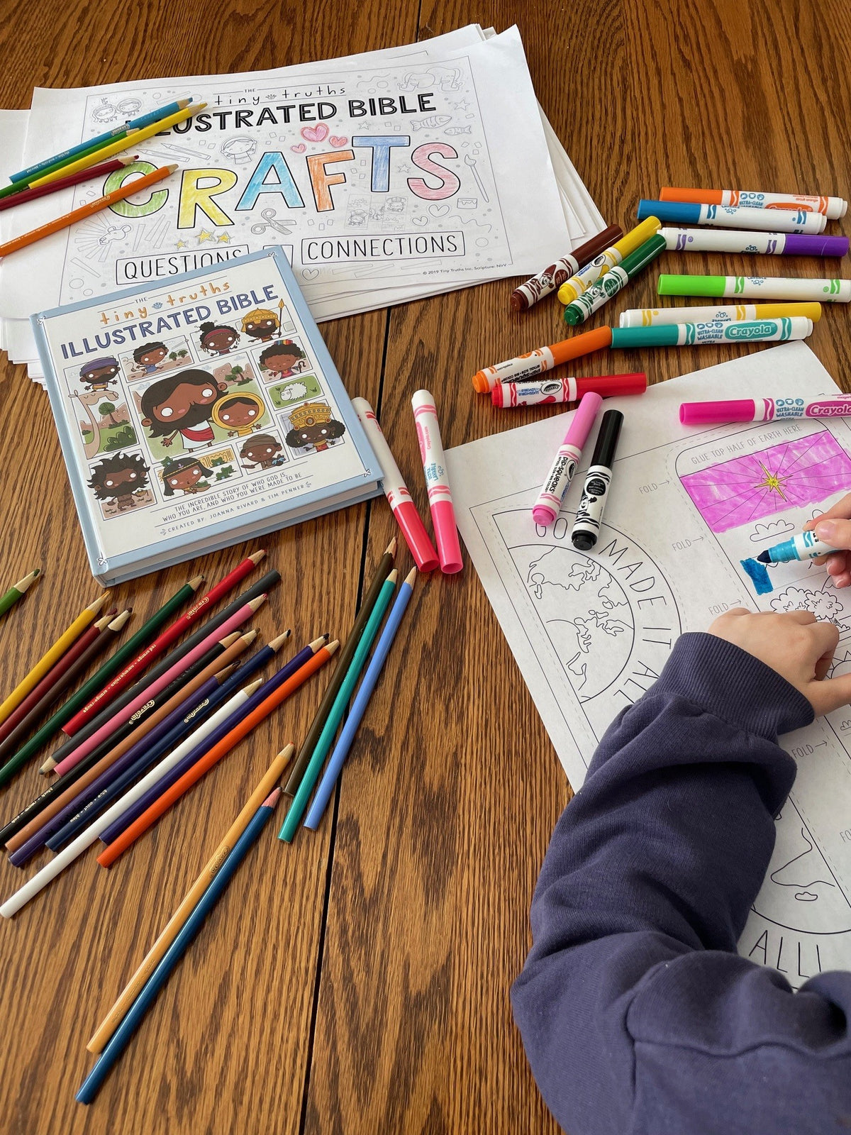 Children's activity book with coloring supplies on a wooden table