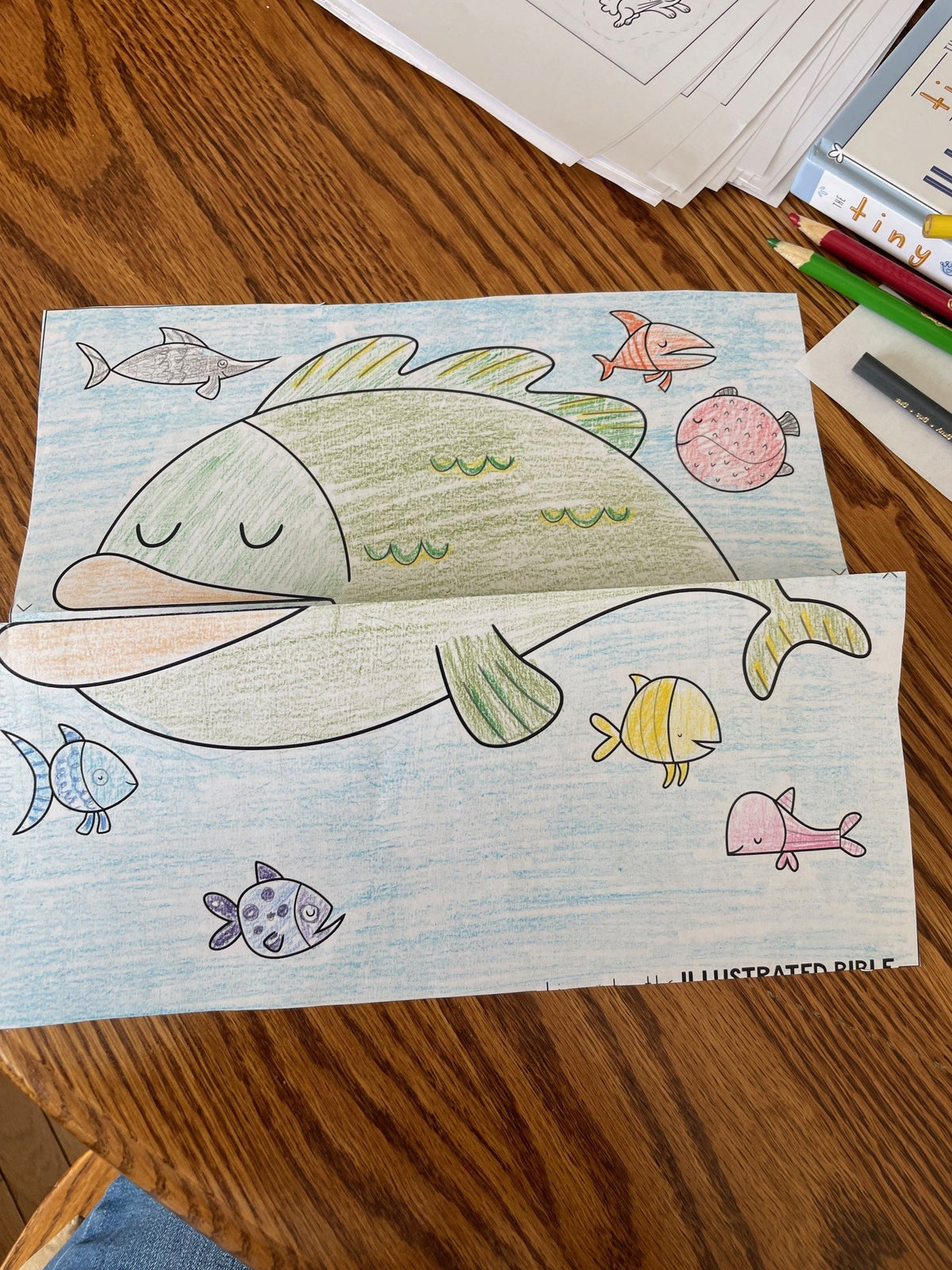 Coloring book with a large fish illustration on a wooden surface