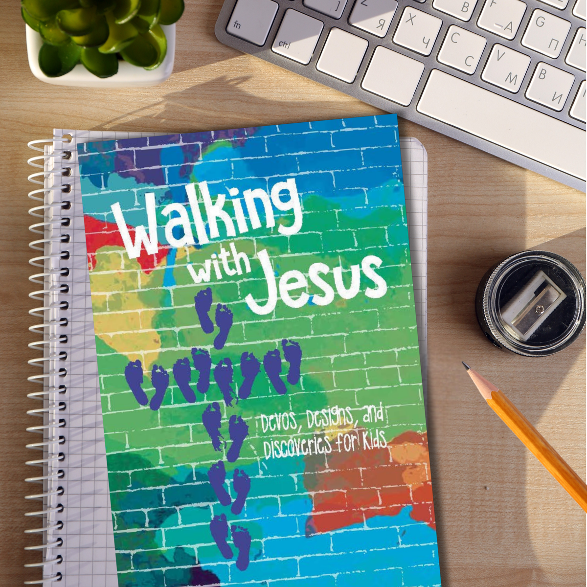 Notebook titled 'Walking with Jesus' on a desk with a keyboard and stationery items by CTA Christ to All & CTAKids.