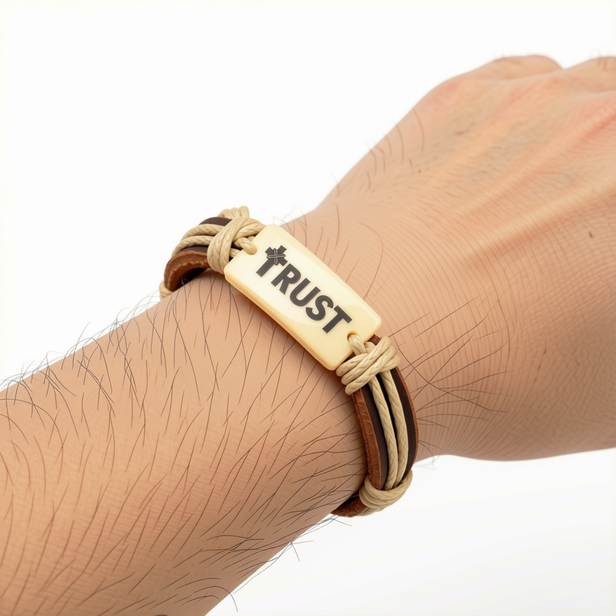 A close-up of a person's wrist wearing a multi-strand bracelet with a central beige rectangular plate engraved with the word 'TRUST' and a small star-like symbol by CTA Christ to All & CTAKids.