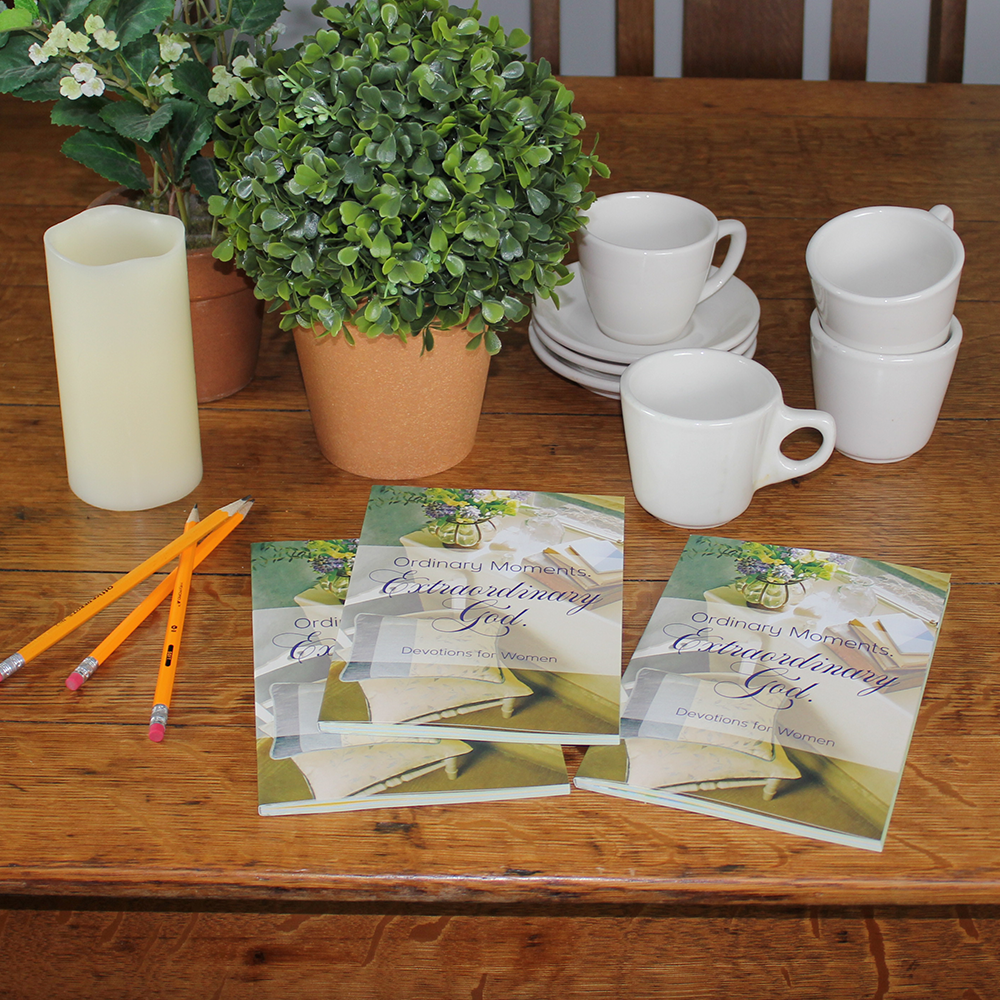 Christian women's devotional books on table with pencils, candle, plants, and mugs