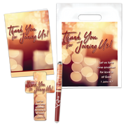 A gift set including a pen, bookmark, brochure holder, and brochure bag with a theme verse from 1 John 4:7 printed on them. The items are displayed with a blurred background.
